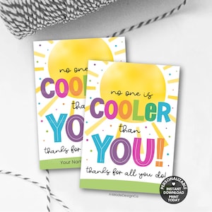 May include: Two white rectangular cards with the text "no one is COOLER than YOU!" in colorful letters. The cards have a yellow sun graphic and the words "thanks for all you do!" at the bottom. The cards are on a white surface.
