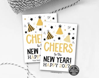 Può includere: Due cartoline rettangolari bianche con testo in glitter dorato che recita CHEERS to the NEW YEAR! HAPPY 2027. Il design include cappellini da festa neri e dorati, stelle nere e piccoli punti dorati. In basso è presente uno spazio per un nome.