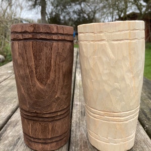 Puede incluir: Dos tazas de madera, una es marr&oacute;n y la otra es de madera clara. Ambas tazas tienen un dise&ntilde;o tallado alrededor del medio.