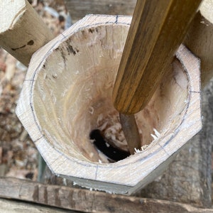 Puede incluir: Un cuenco de madera que se est&aacute; tallando con un cincel. El cuenco est&aacute; hecho de madera clara y tiene una forma redonda. El cincel est&aacute; hecho de madera oscura y tiene una hoja afilada.