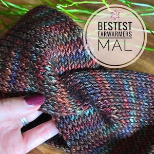 Könnte beinhalten: Mehrfarbige gestrickte Ohrenwärmer in einem braunen, blauen, roten und grünen Farbschema. Die Ohrenwärmer sind in der Mitte gefaltet und haben ein strukturiertes Strickmuster. Der Text "BESTEST EARWARMERS MAL" ist auf dem Bild sichtbar.