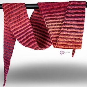 May include: A handmade, crochet scarf in shades of red, pink, and orange. The scarf is striped and hangs from a black bar. The scarf has a pointed end and a small tag with a floral design and text.