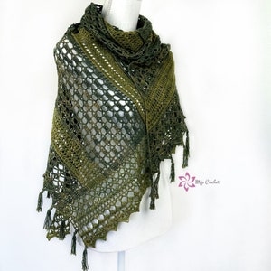 Op de afbeelding: Een groene gehaakte sjaal met een kantpatroon en franjes. De sjaal is over een wit mannequin gelegd.