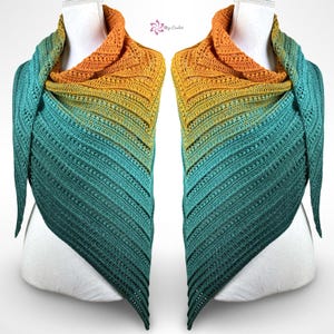 May include: A handcrafted crochet shawl in a gradient of colours, shifting from teal to yellow and finishing in orange. The shawl is displayed on a mannequin, highlighting its triangular form and textured stitch pattern. The design includes the text "Mijo Crochet".