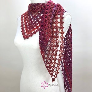 May include: A crocheted shawl in shades of red, orange, and purple. The shawl is made with a delicate openwork stitch and has a fringed edge.