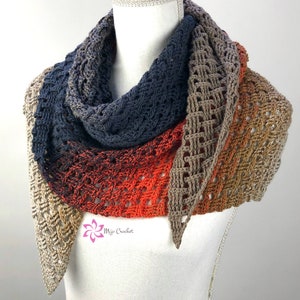 Op de afbeelding: Een gehaakte sjaal met een kleurverloop, beginnend met licht beige, dan overgaand naar donker oranje, gevolgd door donkerblauw en eindigend met licht beige. De sjaal is over een wit mannequin gelegd.