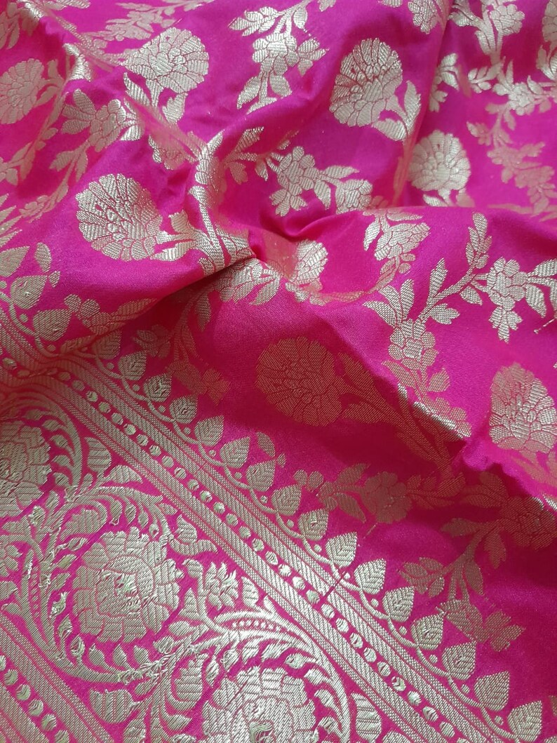 Puede incluir: Tela rosa con un patr&oacute;n floral dorado. La tela tiene un borde con un dise&ntilde;o m&aacute;s intrincado.