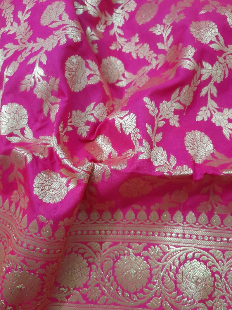 Puede incluir: Una tela rosa con un patr&oacute;n floral dorado. La tela tiene un borde con un patr&oacute;n repetitivo de puntos dorados y hojas.