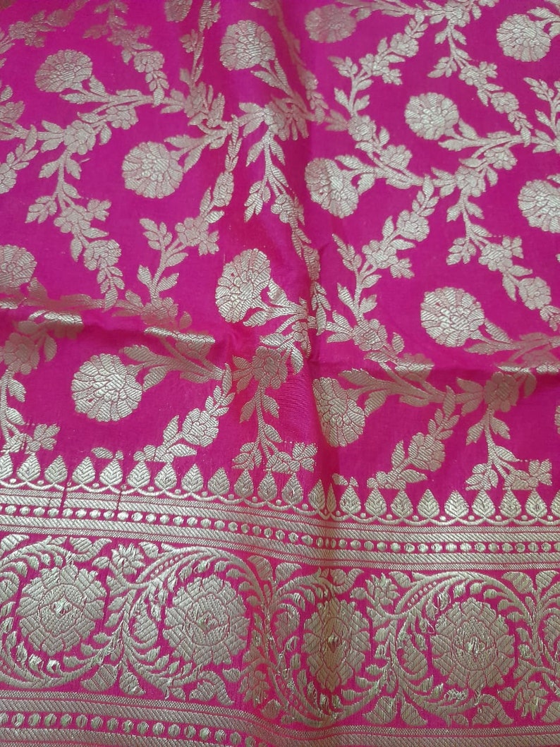 Puede incluir: Tela rosa con un patr&oacute;n floral dorado. La tela tiene un borde con un patr&oacute;n repetitivo de hojas dor&eacute;es y puntos.