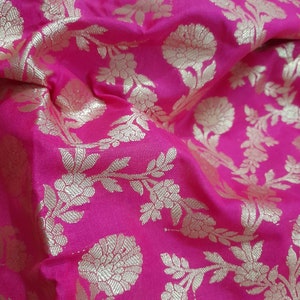 Puede incluir: Tela rosa con un patr&oacute;n floral dorado. La tela tiene un brillo sutil y una textura suave.