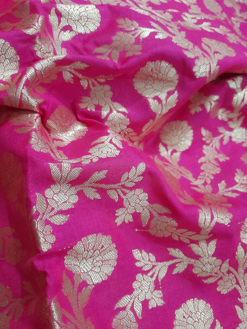 Puede incluir: Tela rosa con un patr&oacute;n floral dorado. La tela tiene un brillo sutil y una textura suave.