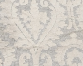 May include: White fabric with a delicate, intricate pattern of floral designs. The fabric has a subtle sheen and a soft, textured feel.