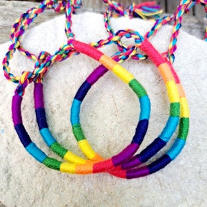 Peut inclure: Trois bracelets d'amitié arc-en-ciel colorés en fil tissé. Les bracelets sont dans les tons de rouge, orange, jaune, vert, bleu, indigo et violet.