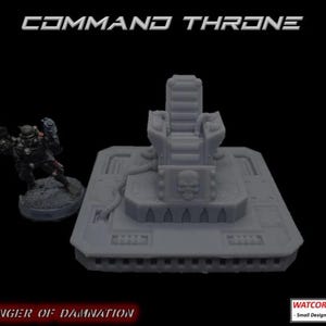 May include: A grey resin miniature command throne featuring a skull emblem on the base, accompanied by a small soldier figurine. The text COMMAND THRONE, HARBINGER OF DAMNATION, and WATCORP DESIGNS - Small Designs, Big Ideas are visible.