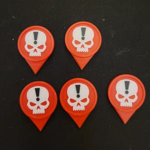 Puede incluir: Seis marcadores de plástico rojo en forma de calavera con un signo de exclamación blanco dentro de la calavera. Los marcadores tienen forma de flecha puntiaguda.
