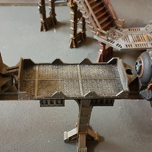 May include: A model train set featuring a brown and grey train carriage, a grey platform, and a black and copper train carriage.