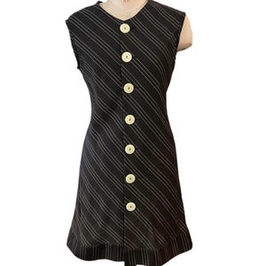 May include: A sleeveless black and white striped dress with a button-up front and a ruffled hem.