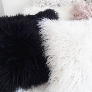 May include: Two fluffy throw pillows, one black and one white. The pillows are made of a soft, plush material and are perfect for adding a touch of comfort and style to any room.