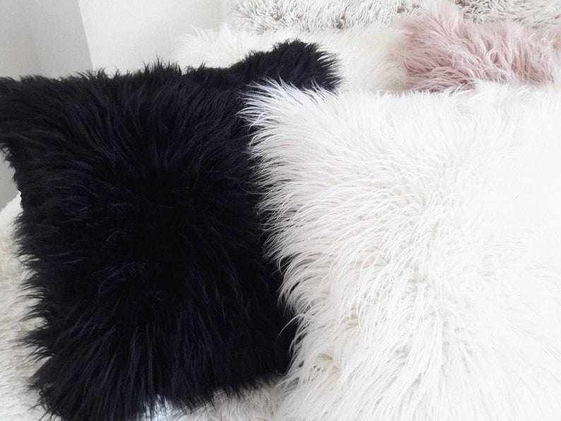 May include: Two fluffy throw pillows, one black and one white. The pillows are made of a soft, plush material and are perfect for adding a touch of comfort and style to any room.