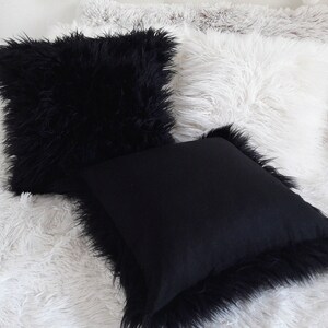 Puede incluir: Tres almohadas decorativas con textura esponjosa. Las almohadas son negras y blancas. Las almohadas est&aacute;n dispuestas sobre una superficie esponjosa blanca.