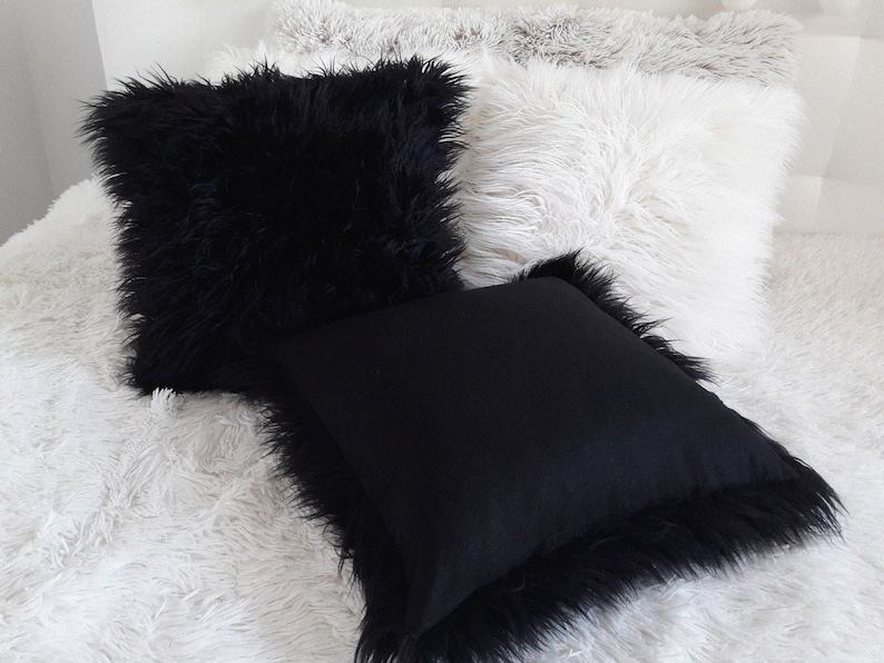 Puede incluir: Tres almohadas decorativas con textura esponjosa. Las almohadas son negras y blancas. Las almohadas est&aacute;n dispuestas sobre una superficie esponjosa blanca.