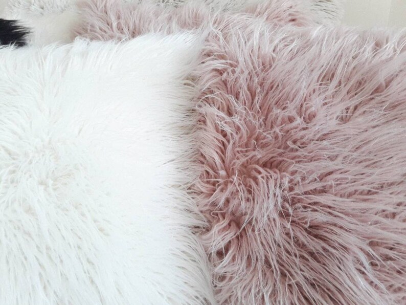 May include: Two fluffy throw pillows, one white and one light pink. The pillows are made of a soft, plush material and would be perfect for adding a touch of comfort and style to any room.