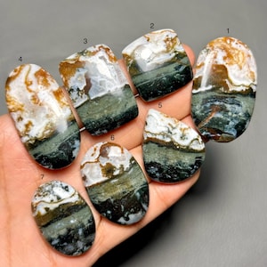 May include: Seven polished gemstones with unique patterns and colors. Each stone features a mix of white, brown, green, and black hues. The shapes vary, including oval, rectangular, and irregular forms, showcasing natural stone variations.