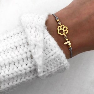 Pulsera con inicial de letra dorada y pata de filigrana de macramé