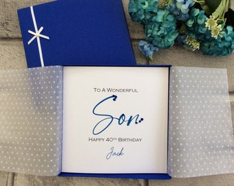May include: A blue card with white polka dot tissue paper inside. The card has a white background with blue text that reads "To a Wonderful Son. Happy 40th Birthday Jack".