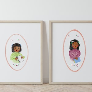 May include: Two framed prints with illustrations of a young girl with brown skin and black hair. The first print says "I Am Smart" and the second print says "I Am Strong".