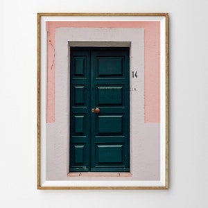 May include: A green wooden door with a brass door handle, set in a pink and white building with the number "14" above the door.