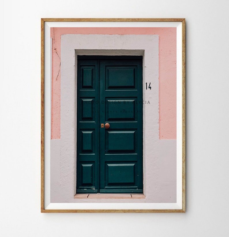 May include: A green wooden door with a brass door handle, set in a pink and white building with the number "14" above the door.