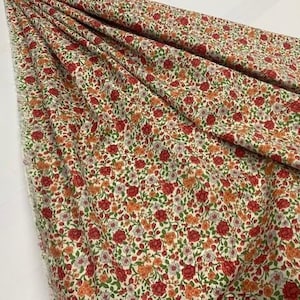 Könnte beinhalten: Weißer Stoff mit einem kleinen floralen Druck mit roten, orangefarbenen und violetten Blüten. Der Stoff hat einen dezenten grünen Hintergrund.