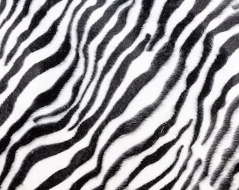 May include: Black and white zebra print fabric with a soft, fuzzy texture.