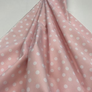 May include: Pink fabric with white polka dots. The fabric has a corduroy texture.