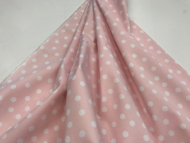 May include: Pink fabric with white polka dots. The fabric has a corduroy texture.