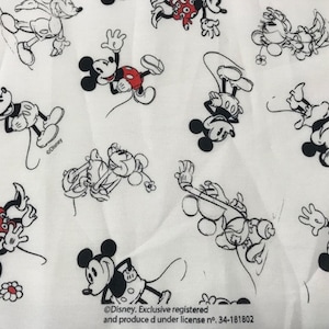 Puede incluir: Tela blanca con un patrón repetido de personajes de Mickey Mouse negros y rojos. La tela tiene el texto "©Disney. Exclusive registered and produce d under license no. 34-181802".
