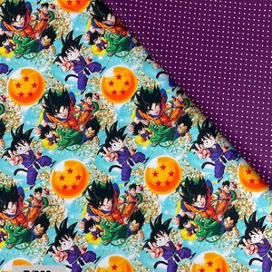 Puede incluir: Una tela azul y blanca con un patrón repetido de un personaje de dibujos animados con cabello negro, un atuendo rojo y naranja, y una esfera amarilla con estrellas rojas. La tela tiene un efecto de brillo dorado. La tela está etiquetada como "D/333".