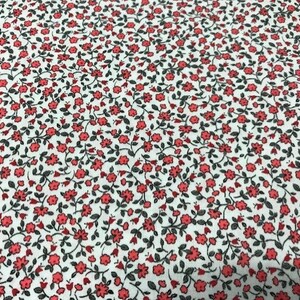 May include: White fabric with a small-scale floral print featuring red flowers and dark green leaves.