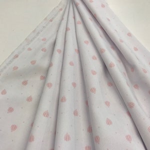 May include: White fabric with a pink polka dot pattern of hot air balloons. The fabric has a ribbed texture.
