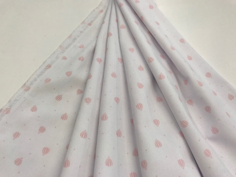 May include: White fabric with a pink polka dot pattern of hot air balloons. The fabric has a ribbed texture.