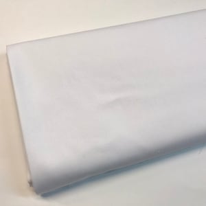 Puede incluir: Una muestra de tela blanca, que muestra la textura y el color del material.