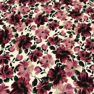 May include: A white fabric with a repeating pattern of dark pink and burgundy flowers. The flowers are stylized and have a watercolor effect.