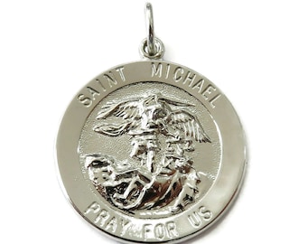 May include: A silver-colored Saint Michael pendant with a detailed relief of Saint Michael slaying a demon. The words "SAINT MICHAEL" and "PRAY FOR US" are inscribed around the edge of the circular pendant. The pendant has a small loop at the top for a chain.