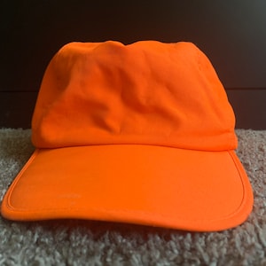 May include: A bright orange baseball cap with a curved brim.