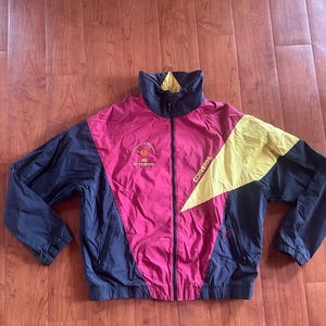 May include: A vintage Converse windbreaker jacket in a color block design. The jacket features a high collar, a full zipper, and a mix of colors including navy blue, magenta, and yellow. The text "University of Wisconsin" and "1993 Big Champions" is printed on the front.
