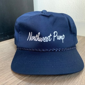 May include: A navy blue baseball cap with a white embroidered logo that says "Northwest Pump".
