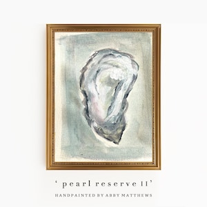 Op de afbeelding: Waterverfschilderij van een oesterschelp in een gouden lijst. De schelp is geschilderd in tinten grijs, wit en roze tegen een lichtblauwgroene achtergrond. De tekst "pearl reserve II" en "handpainted by Abby Matthews" staat onderaan.