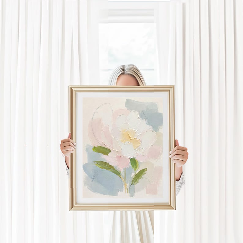 May include: A framed painting featuring an abstract floral design with thick, textured brushstrokes in shades of soft pink, pale yellow, sage green, and muted blue on a cream-colored background, encased in a metallic gold-toned rectangular frame.
