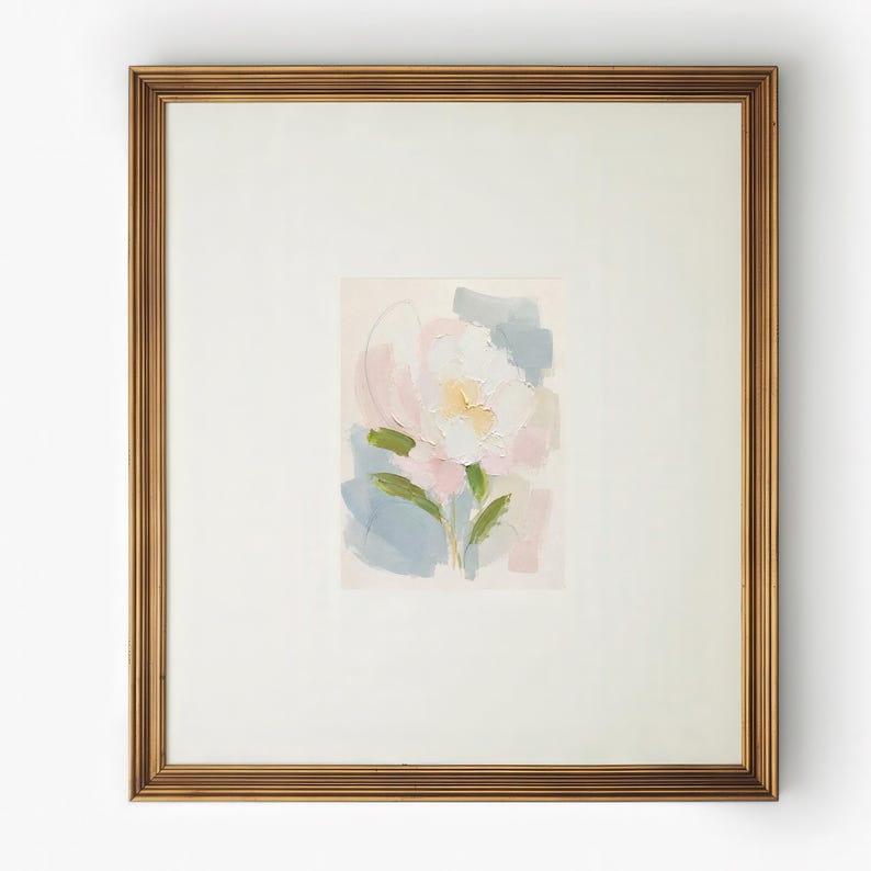 May include: A framed painting featuring an abstract floral subject with thick, textured brushstrokes in shades of white, soft pink, pale yellow, and muted blue, set within a wide off-white mat and a metallic gold-toned rectangular frame.